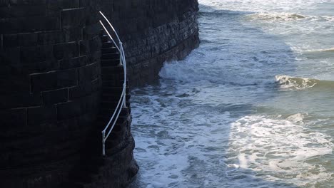 Close-up-of-spiral-steps-near-Aberystwyth-Harbour-in-Ceredigion,-West-Wales,-with-waves-crashing
