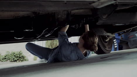 Woman-in-early-20s-checking-under-the-hood-of-a-truck-and-going-under-the-truck-to-find-and-fix-mechanical-problem