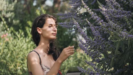 Smiling-woman-smells-the-scent-of-purple-lilac-flowers-in-the-botanical-gardens-of-the-perfumery-museum