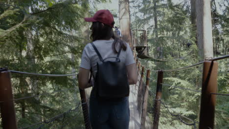Following-a-young-hiker-as-she-walks-across-a-suspension-bridge-in-the-forest-on-a-beautiful-summer-day
