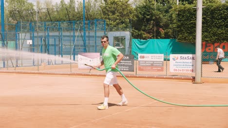 Maintenance-of-artificial-tennis-clay-court-with-water-hose