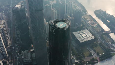 Slow-aerial-pivot-around-the-top-of-IFC-Tower-with-helipad-and-Four-seasons-hotel-on-the-top-floors,-in-early-morning