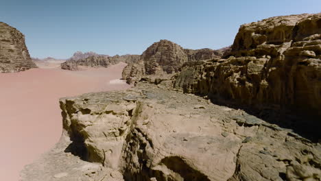 Flying-Through-Granite-Rock-Cliffs-And-Vast-Sand-Dune-In-Wadi-Rum,-Jordan