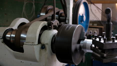 Old-Lathe-with-spinning-pulley-and-machining-an-aluminum-piece-leaving-shaving-long-shot