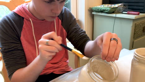 Teenage-boy-painting-mason-jars-with-white-paint-for-arts-and-crafts
