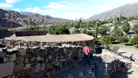 Beautiful-landscape-of-the-pre-Inca-ruins-of-Pucara-de-Tilcara-on-a-sunny-day-and-a-brunette-tourist-walking-through-its-paths