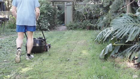 Man-mowing-the-lawn-in-a-garden-going-backwards-and-forwards-HD-footage-slow-motion