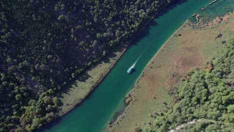 Tourist-ferry-ship-traveling-through-turquoise-river-in-Croatia,-aerial