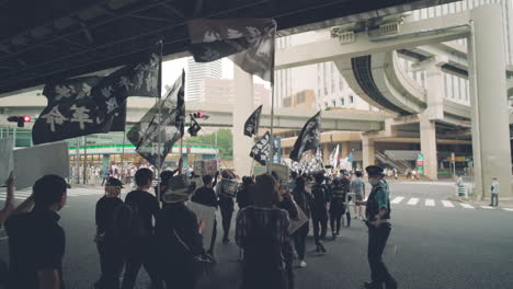Policeman-Escorts-Protesters-Holding-Flags-And-Placards-Marching-At-A-Solidarity-For-Hong-Kong-Protests-In-Tokyo,-Japan