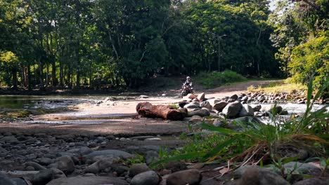 Person-on-an-old-motorcycle-crossing-a-river-with-low-water-level-on-a-sunny-day-in-Costa-Rica