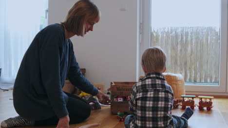 Mutter-Und-Kind-Sitzen-Auf-Dem-Boden-Und-Bauen-Gemeinsam-Eine-Spielzeugeisenbahn