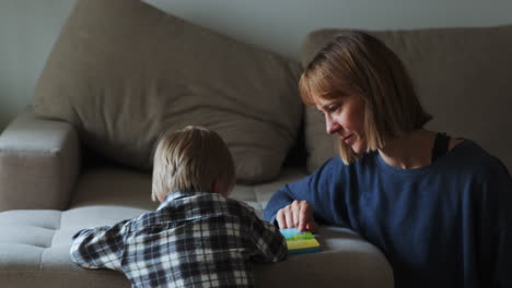 Junge-Und-Mutter-Lesen-Ein-Buch,-Während-Sie-Neben-Dem-Sofa-Sitzen