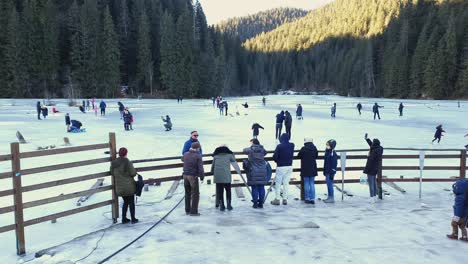 People-Spending-Leisure-On-Frozen-Red-Lake-In-Romania-On-A-Sunny-Winter-Morning---high-angle,-wide-shot