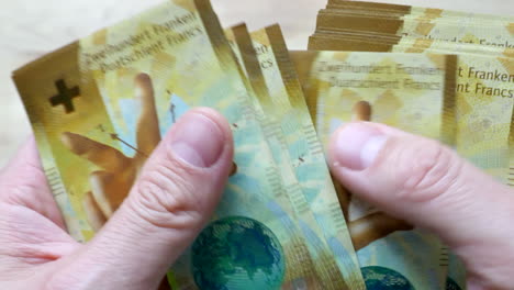 Close-up-of-man-counting-several-chf-two-hundred-swiss-franc-banknotes-indoors-at-home