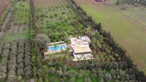 Eine-Wunderschöne-Villa,-Die-Mit-Traditioneller-Marokkanischer-Ästhetik-Dekoriert-Ist,-Mit-Einem-Pool,-Der-Von-Enormen-Variationen-Von-Bäumen-Und-Sträuchern-Umgeben-Ist,-In-Der-Nähe-Einer-öffentlichen-Straße