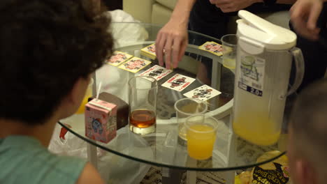 Friends-eat-chips,-drink-juice-and-playing-cards-in-Hong-Kong-over-a-glass-table