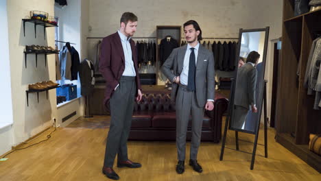 Customer-describing-boutique-assistant-how-new-suit-feels-at-fitting