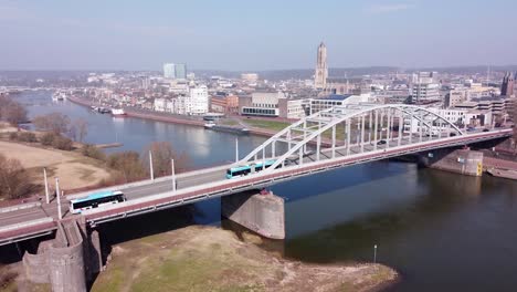 Trolley-Bus-drives-over-Rhine-Bridge-in-Arnhem,-Gelderland,-Netherlands---Aerial