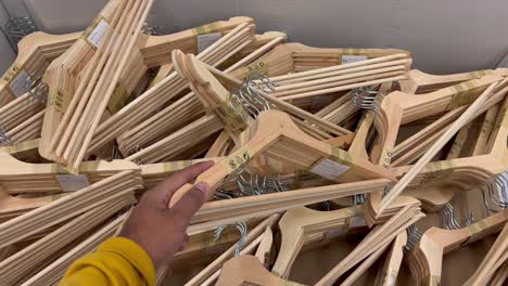 Overview-shot-of-hands-checking-a-bunch-of-wooden-coat-hanger-on-sale-in-a-mall
