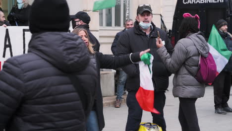 Mujer-Enojada-Con-Bandera-Italiana-Grita-Para-Protestar-Contra-El-Gobierno-Con-Multitud-Y-Carabinieri-En-El-Fondo-En-Piazza-Xxv-Aprile-En-Milán,-Italia