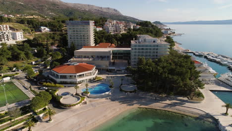 Coastal-hotel-building-with-football-field-and-luxury-yachts-in-Croatia,-Split-city,-aerial-drone-view