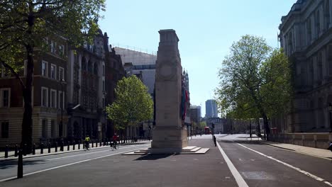 Coronavirus-lockdown---cyclists-riding-pass-the-Cenotaph-on-the-empty-London-street-of-Whitehall---a-normally-busy-tourist-location