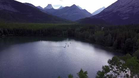 Paddle-boarders-and-boat-on-a-mountain-lake-pull-out-Rockies-Kananaskis-Alberta-Canada