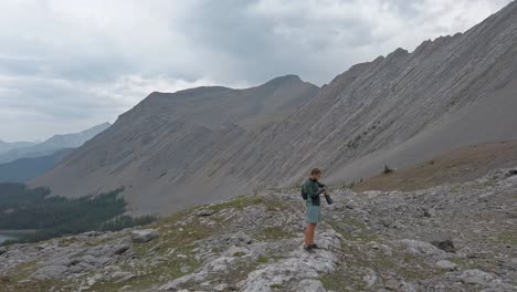 Hiker-checking-watch-walking-trough-mountain-amphitheater-Rockies-Kananaskis-Alberta-Canada