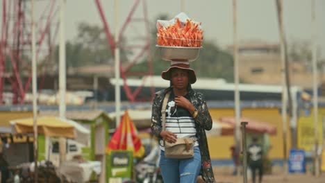 African-Female-Street-Food-Vendor-Walking-in-slowmotion-with-Package-on-Head---Togo,-Africa