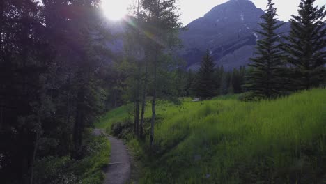 Park-trail-with-empty-bench-mountain-sun-flare-Rockies-Kananaskis-Alberta-Canada
