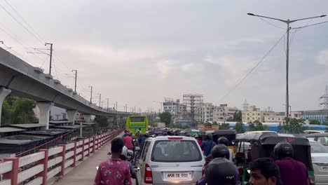 Several-buses,-vehicles,-and-bikes-are-snarled-in-traffic-and-a-isolated-flyover-passes-through-the-city