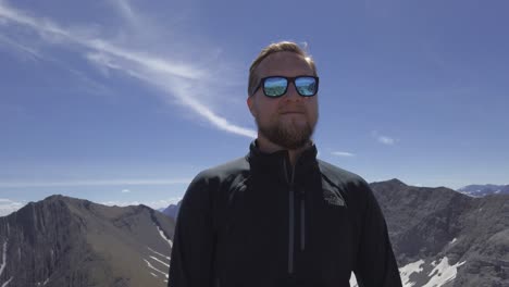 Hiker-standing-on-top-of-mountain-close-up,-reflective-sunglasses-Rockies-Kananaskis-Alberta-Canada