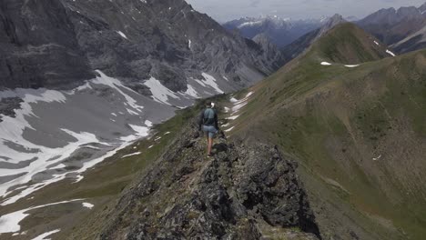 Hiker-on-mountain-ridge-revealed-walking-enjoying-the-view,-Rockies-Kananaskis-Alberta-Canada