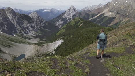 Hiker-walking-on-ridge-looking-at-lake-Rockies-Kananaskis-Alberta-Canada