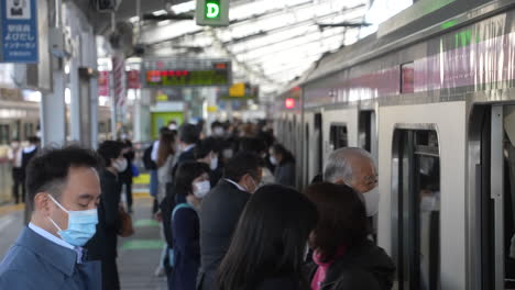 Bahnhof-Mit-Passagieren,-Die-Eine-Schützende-Gesichtsmaske-Tragen,-Die-In-Tokio,-Japan,-In-Den-Zug-Ein--Und-Aussteigen