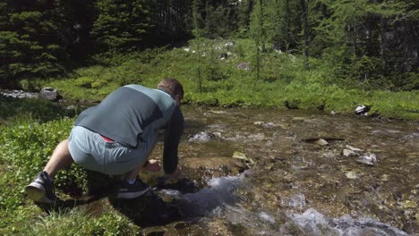 Hiker-drinking-water-from-mountain-creek-Rockies,-Kananaskis,-Alberta-Canada