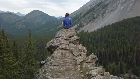 Hiker-sitting-reading-on-ledge-approached-Rockies-Kananaskis-Alberta-Canada