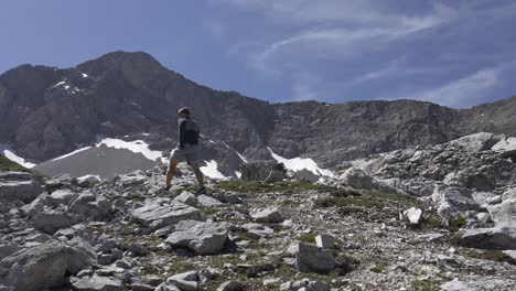 Hiker-on-rock-terrain-ascending-mountain-tilt-pan-followed-Rockies,-Kananaskis,-Alberta-Canada