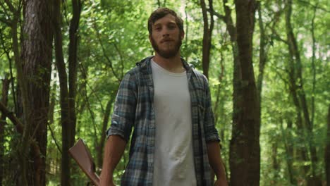 Proud-caucasian-North-American-male-standing-in-the-forest-with-shotgun-in-his-hand-looking-straight-at-the-camera