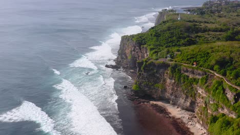 Slow-aerial-push-in-of-ocean-waves-by-cliffs-in-Uluwatu,-Indonesia