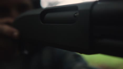 young-caucasian-male-holding-shotgun-focus-on-the-aim-target-victim-,-extremely-close-up-of-pistol-weapon
