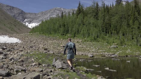 Hiker-on-trail-by-pond-pine-forest-Rockies-Kananaskis-Alberta-Canada