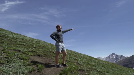 Hiker-pointing-to-direction-mountain-pan,-Rockies,-Kananaskis,-Alberta-Canada