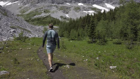 Hiker-on-mountain-trail-in-valley-followed-,-Rockies,-Kananaskis,-Alberta-Canada