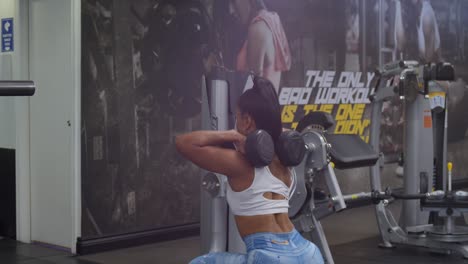 Sexy-female-bodybuilder-performing-squats-at-the-gym-with-dumbells-over-her-shoulder
