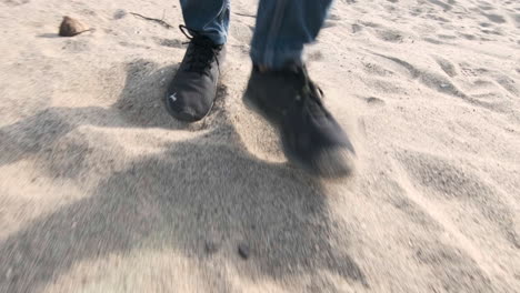 Feet-shod-with-sneakers-walking-on-beach-sand-in-sunny-day