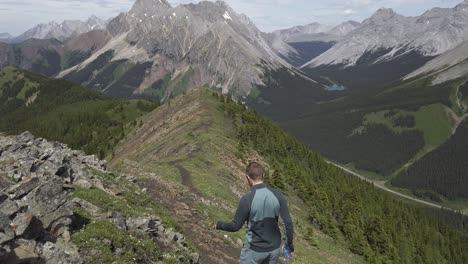 Hiker-walking-down-the-ridge-with-distant-road-Rockies-Kananaskis-Alberta-Canada