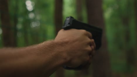 Man-holding-hand-gun-ready-to-shoot-in-the-forest,-serial-killer-looking-for-revenge-concept-of-crime-and-fire-arm-assault