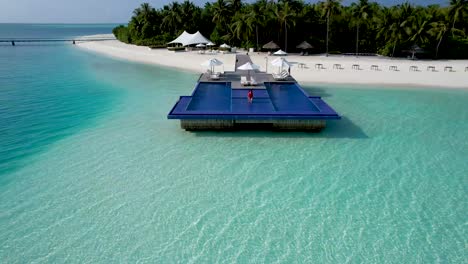 Luftaufnahme-Einer-Frau,-Die-Im-Roten-Badeanzug-In-Den-überlaufpool-über-Dem-Klaren-Blauen-Wasser-Im-Malediven-Luxusresort-Geht