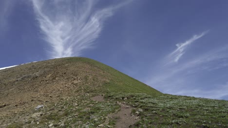 Hiker-scouting-resting-on-Mountain-side-pan-tilt,-Rockies,-Kananaskis,-Alberta-Canada